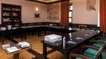 Un salón de conferencias con una larga mesa, sillas, un proyector y libros.