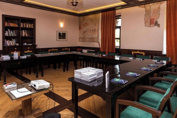 A conference room with a long table, chairs, a projector, and books. - Castle Hotel Daniel (Bradut)