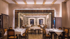 A restaurant with wooden beams, stone walls, and tables set for dining. - Castle Hotel Daniel (Bradut)
