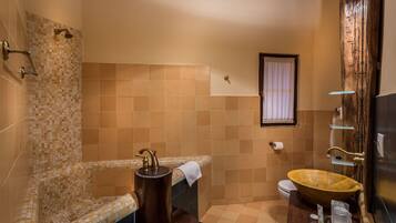 Ein Badezimmer mit einer Dusche mit Mosaikfliesen, einem Holzkosmetikschrank mit Waschbecken und einer Toilette.