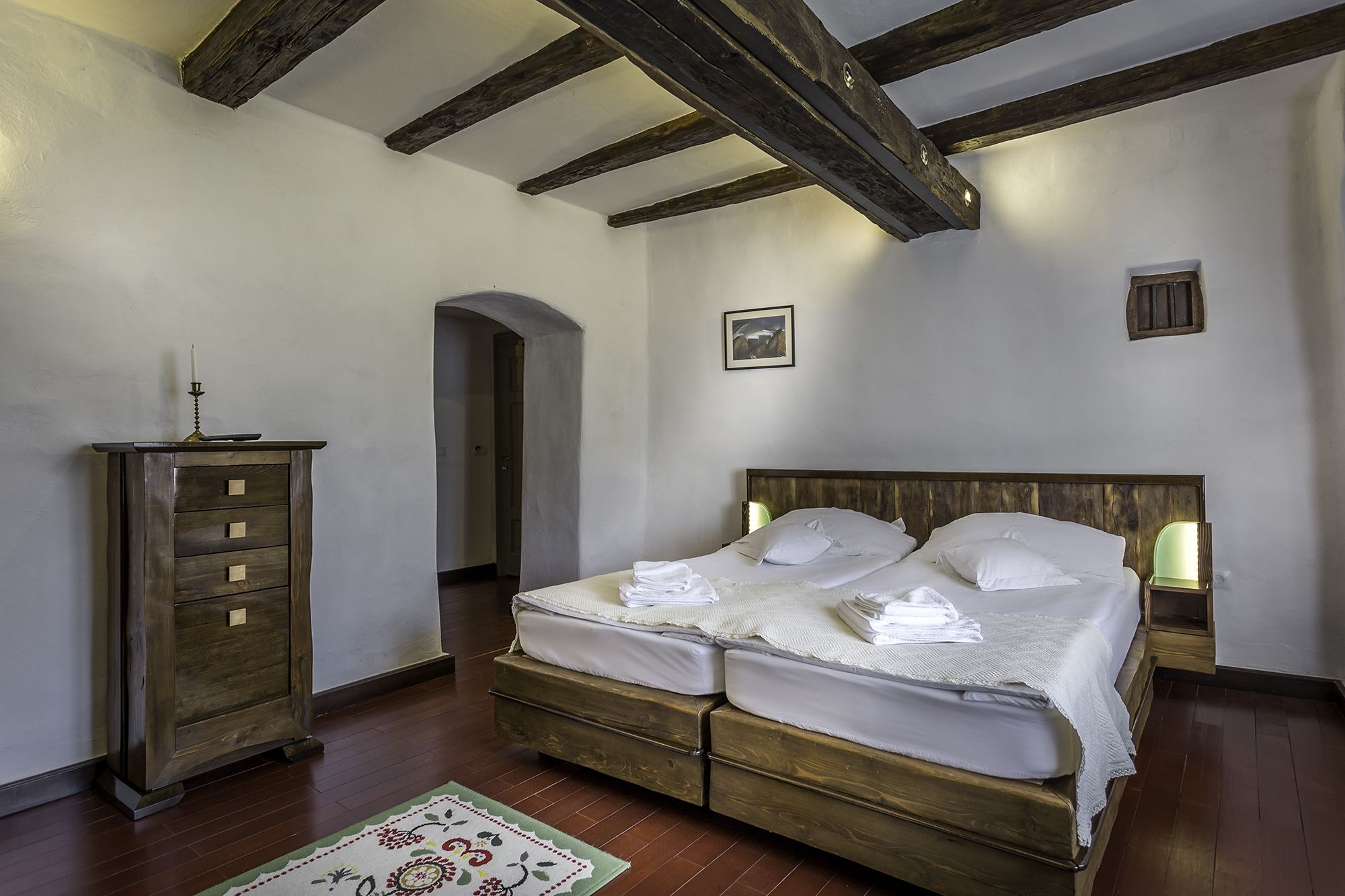 Quarto com cama de madeira, penteadeira e uma pequena imagem na parede.