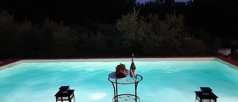 En sÀsongsöppen utomhuspool, parasoller och solstolar