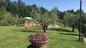 A park with a playground, a flower bed, and a lamp post. - Il Poggio (Pontedera)