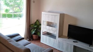A living room with a sofa, a TV, a cabinet, and a potted plant. - Il Poggio (Pontedera)