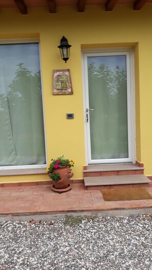 Un edificio amarillo con un ventanal grande, una puerta y una planta en maceta en los escalones.