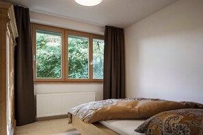 Un dormitorio con cama de madera, una ventana con cortinas y un radiador.