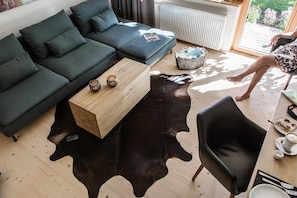 Una sala de estar moderna con un sofá seccional, una mesa de centro de madera, un tapete de cuero negro y un sillón de cuero negro.