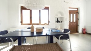 A dining area with a table, chairs, a laptop, and a woven basket. - Villa Ikaros (Rethymno)