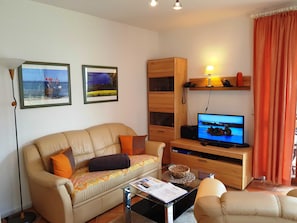 A living room with a sofa, a coffee table, a television, and a bookshelf.