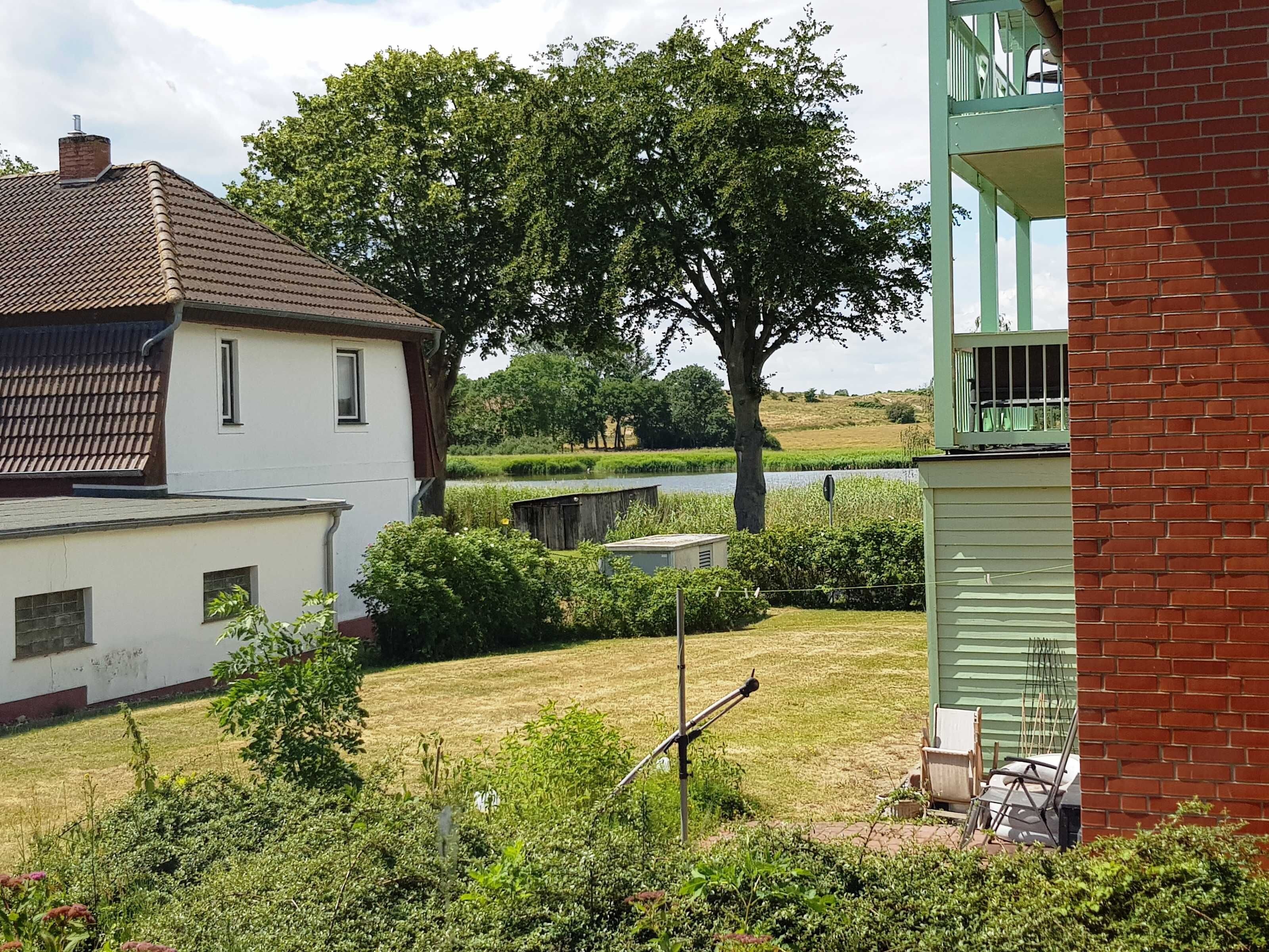 Ein Wohngebiet mit einem weißen Haus, einem grünen Gebäude mit Balkon und einem Baum im Hintergrund.