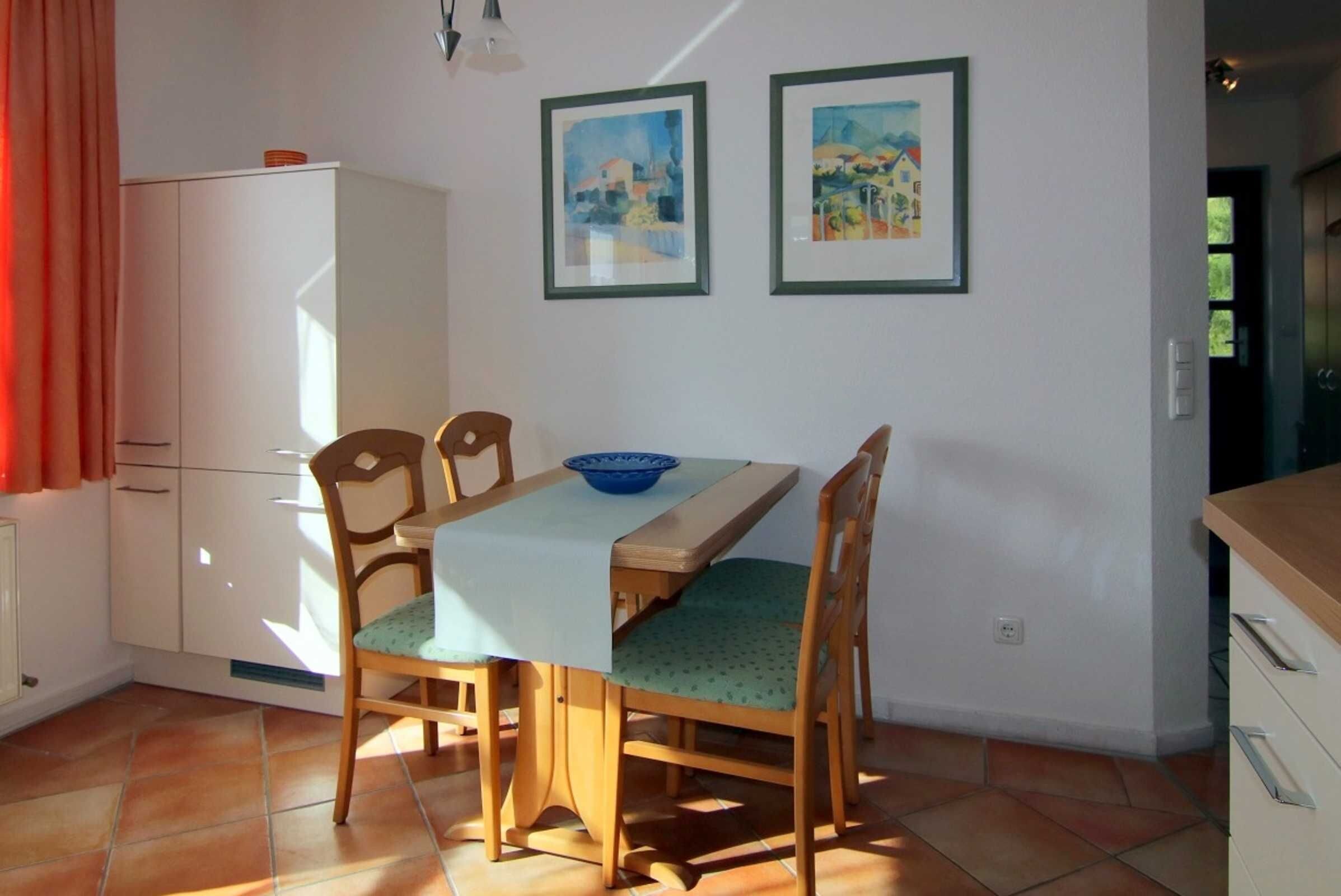 Uma sala de jantar com mesa, cadeiras e duas molduras na parede.