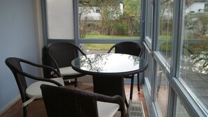 A glass-enclosed patio with wicker furniture and a round table. - Apartment 01 in the fisherman's house with terrace - Apartment Fischers Fritze with winter garden and (Sellin)