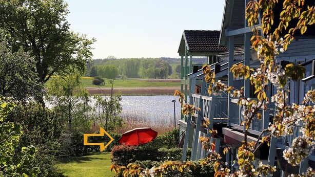A building with a view of a lake, a red umbrella, and a pathway leading to the lake. - Apartment 01 in the fisherman's house with terrace - Apartment Fischers Fritze with winter garden and (Sellin)