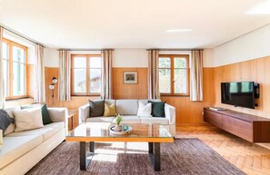 A living room with a sofa, coffee table, TV, and wooden panel walls. - Apartment 1, comfort and comfort (4 Edelweiss) - Haus Kammern 168 (Egg)