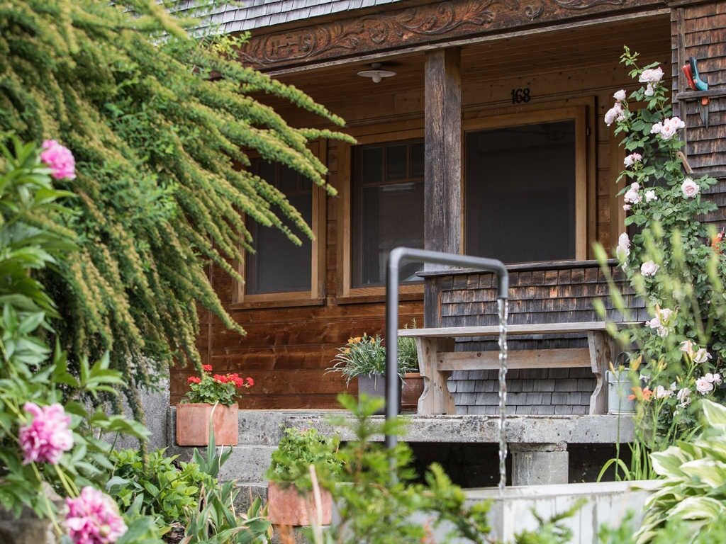 A wooden cabin with a porch, a window, and a number '168' on the wall.