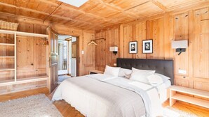 A wooden-paneled bedroom with a bed, bedside tables, a hanging light, and a view through an open door. - Apartment 1, comfort and comfort (4 Edelweiss) - Haus Kammern 168 (Egg)