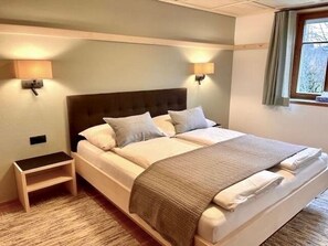 A hotel room with a bed, bedside lamps, a nightstand, and a window with curtains. - Apartment 1, comfort and comfort (4 Edelweiss) - Haus Kammern 168 (Egg)