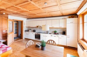 Una cocina moderna con armarios blancos, una mesa de comedor de madera y un suelo con patrón de espiga.