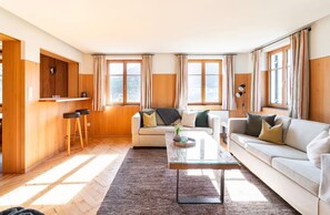 A living room with a sofa, coffee table, and a wooden wall with a mounted deer head.