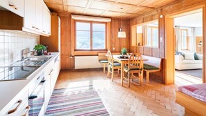 A wooden interior with a kitchen, dining area, and a view through an open door. - Apartment 1, comfort and comfort (4 Edelweiss) - Haus Kammern 168 (Egg)