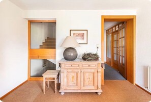 A room with a wooden cabinet, a small table, a lamp, a framed picture, and a staircase. - Apartment 1, comfort and comfort (4 Edelweiss) - Haus Kammern 168 (Egg)