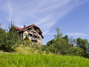 A multi-story building with balconies, surrounded by greenery and trees.