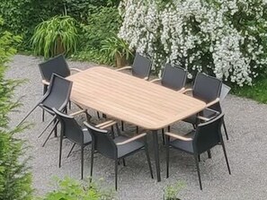 A rectangular wooden table surrounded by six chairs with black frames and dark cushions, set on a gravel surface with greenery in the background. - House in Kammern: Top-Notch Property with Spacious 100 m² of Comfort and a Balcony with Mountain Views - House (Egg)