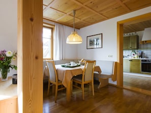 A dining area with wooden furniture, a table with a green tray, and a hanging light fixture.