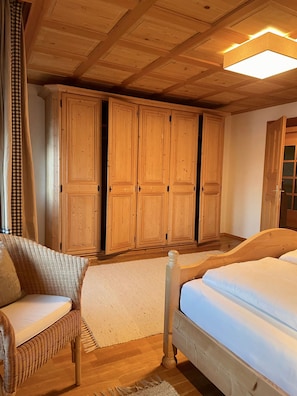 A wooden bedroom with a bed, a chair, and a wardrobe.