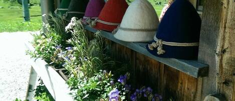 A wooden shelf with colorful hats and a row of potted plants.