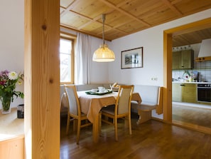 A dining area with wooden furniture, a table with a green tray, and a hanging light fixture. - Vacation apartment 2, spacious comfort, balcony (4 Edelweiss) - Haus Kammern 168 (Egg)