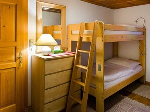 A bunk bed with a ladder, a desk with a lamp, and a mirror.
