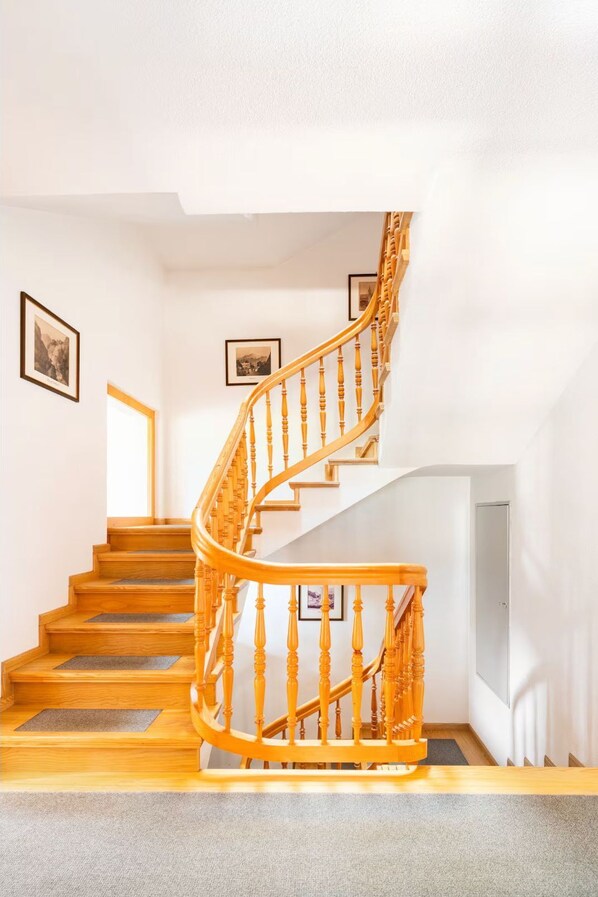A spiral staircase with wooden steps and balusters, leading to an upper floor.