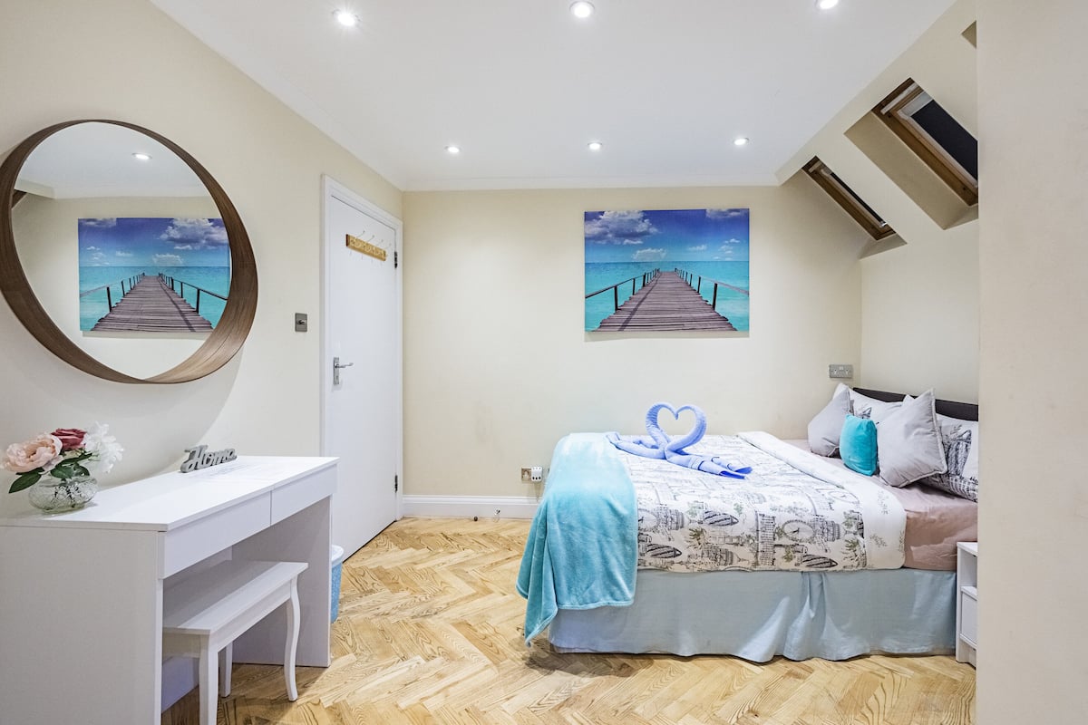 A bedroom with a bed, a desk, and a mirror.