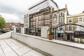 A building under construction with scaffolding, a potted plant, and a storefront with a sign. - Magic Properties (London)