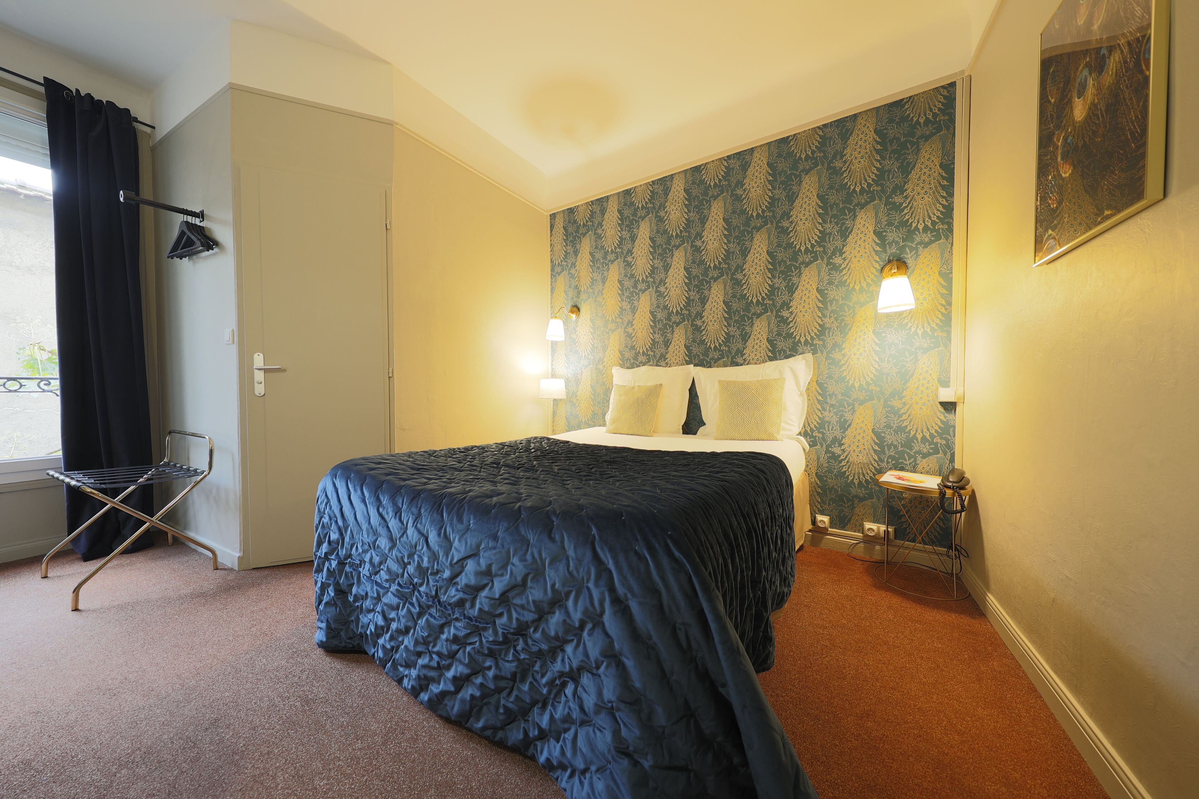 Ein Hotelzimmer mit einem Bett, einem an der Wand montierten Bügelbrett und zwei Nachttischlampen.