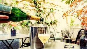 A bottle of champagne being poured into a glass on a table. - Hôtel Azur Reims (Reims)