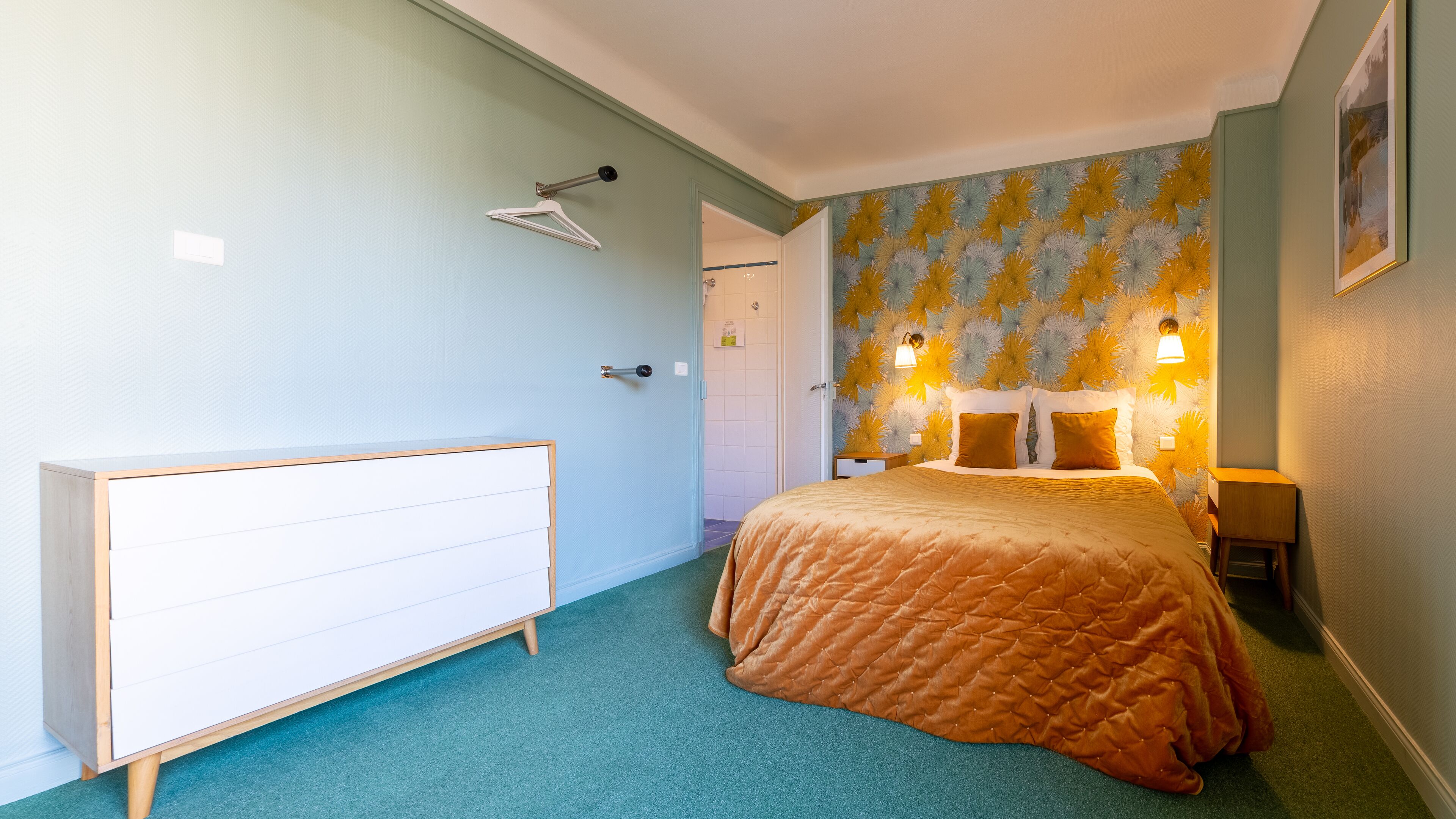 Ein Schlafzimmer mit einem Bett, einer Kommode, einer Tür und einer Wand mit einem Dekor.
