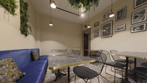 A dining area with a blue sofa, a marble table, black chairs, and framed pictures on the wall. - Hôtel Azur Reims (Reims)