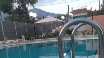 A swimming pool with clear blue water, a metal pool ladder, and tiled edges.