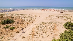 A beach with a wooden boardwalk, sandy dunes, and beach umbrellas.