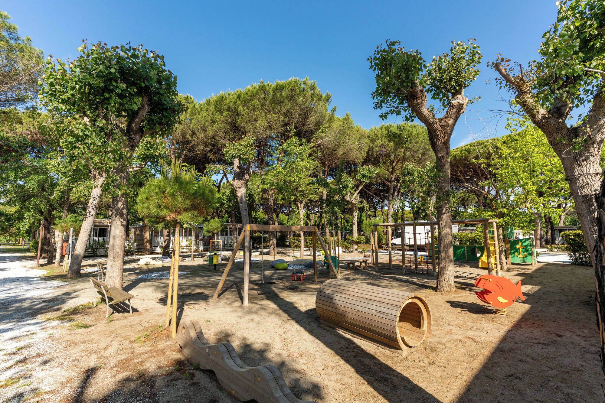 A playground with swings, a slide, and a log cabin structure.