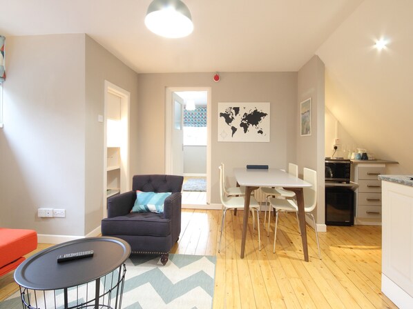 A modern living room with a sofa, a dining table, and a kitchen area. - KC Accommodation (Dungannon)