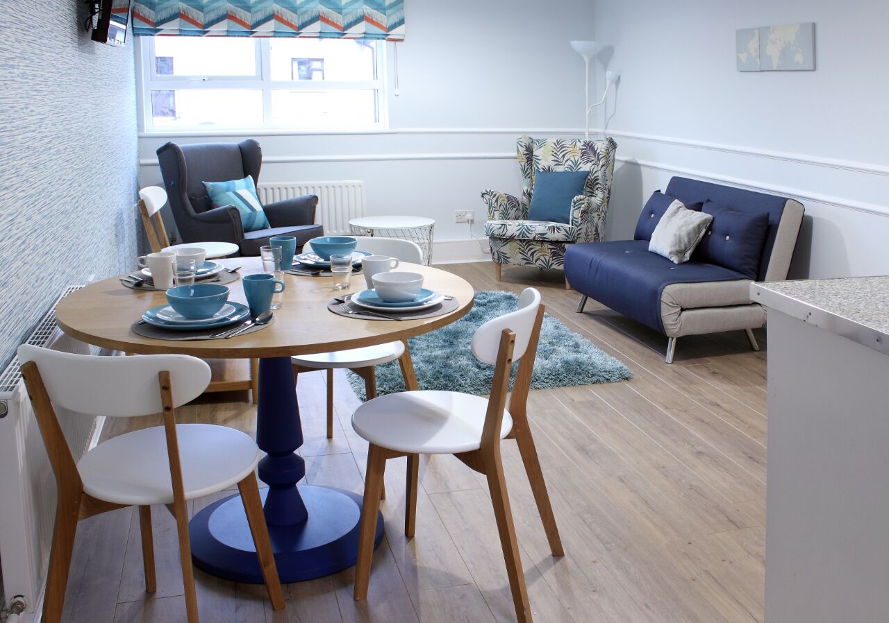 Een eetgedeelte met een ronde tafel, vier stoelen en een blauw-wit kleurenschema.