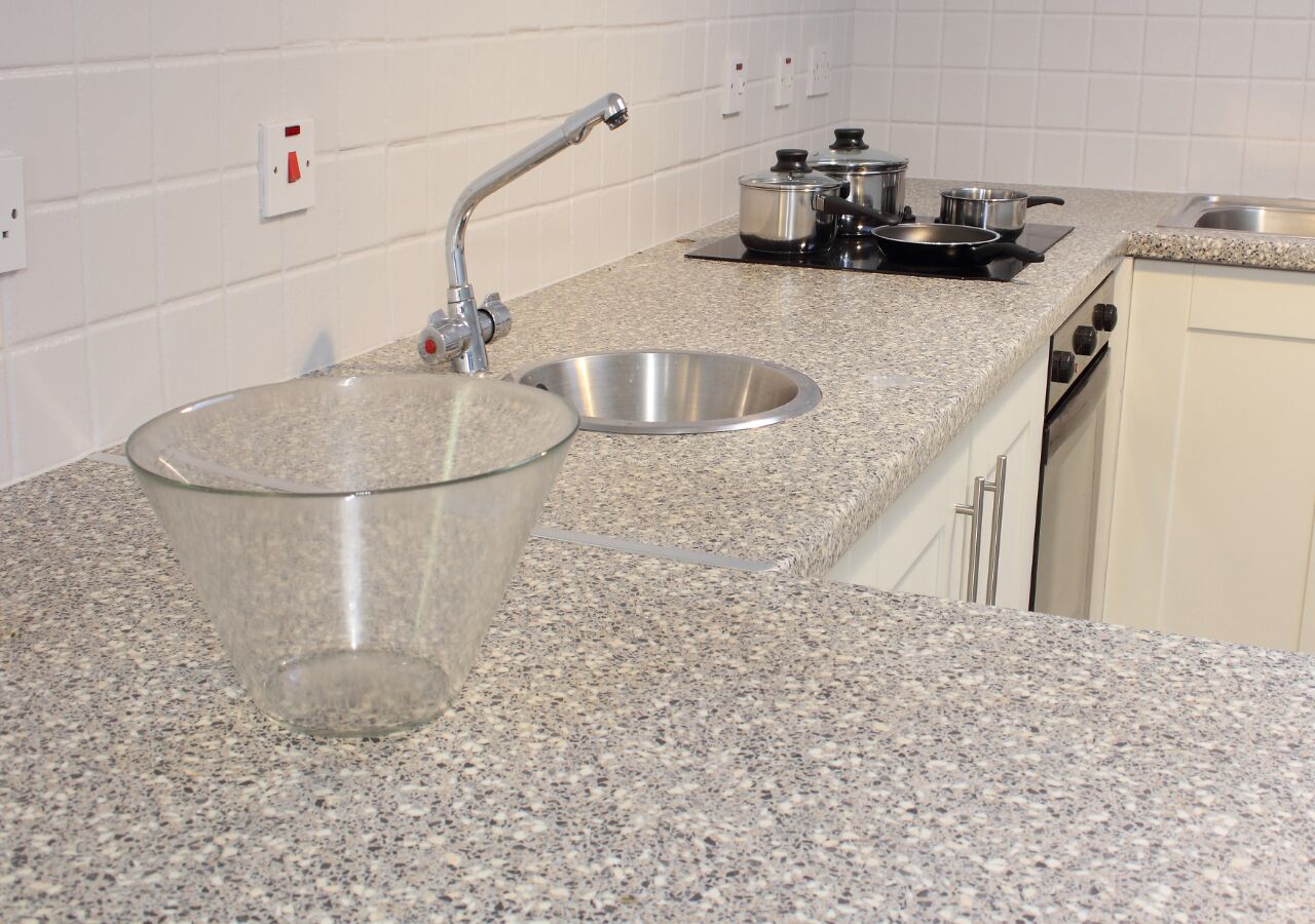 A kitchen with granite countertops, stainless steel sink, and a stove.