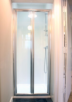 A glass-enclosed shower stall with a showerhead and control panel. - KC Accommodation (Dungannon)