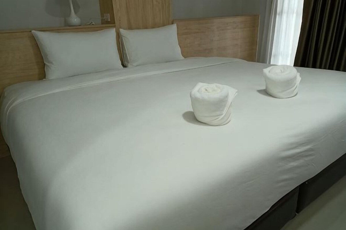 A neatly made bed with two white towels placed on it.