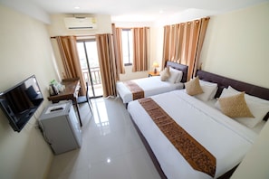 Quarto de hotel com duas camas, televisão, escrivaninha com cadeira e ar condicionado.