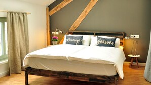 Un dormitorio con estructura de cama de madera, una pared oscura y una ventana con cortinas.
