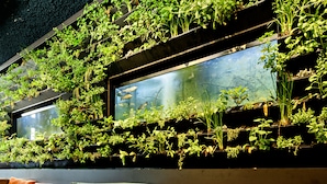 A modern interior with a green wall of plants, a large aquarium, and a leather sofa with cushions. - Conscious Hotel Westerpark (Amsterdam)